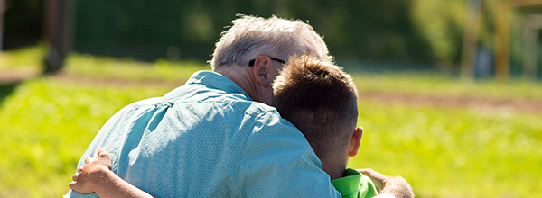 An adult hugging a child on a bench, looking from behind